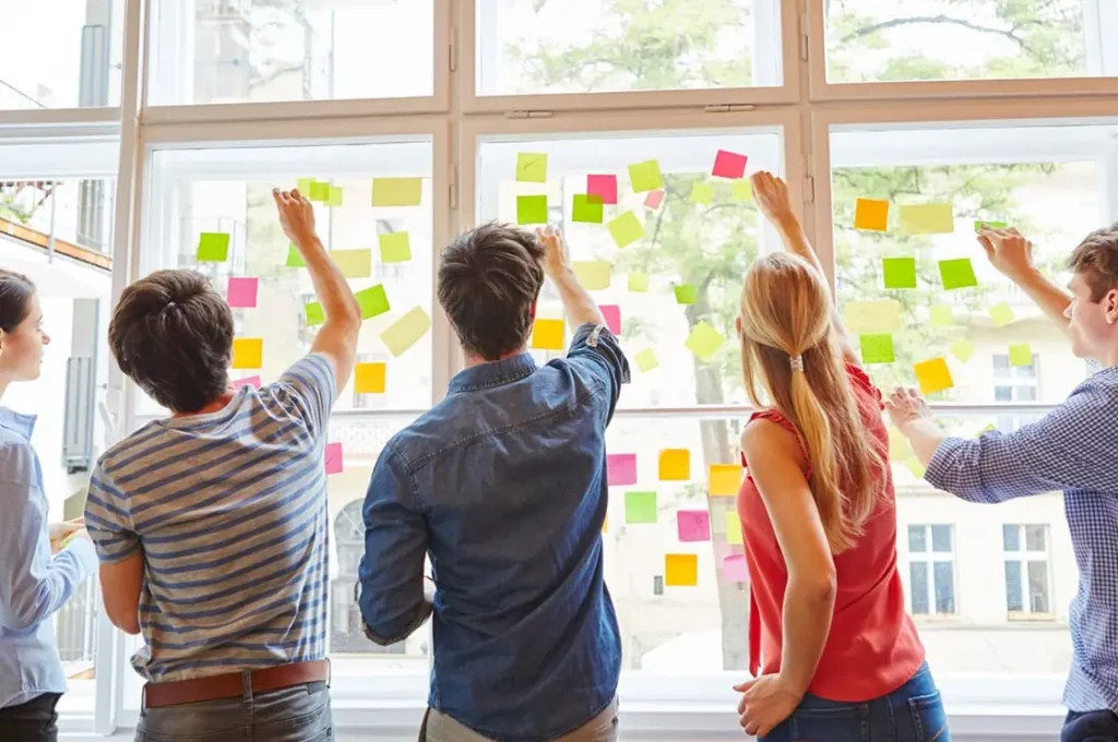 Young academics brainstorming with post-it notes on a window